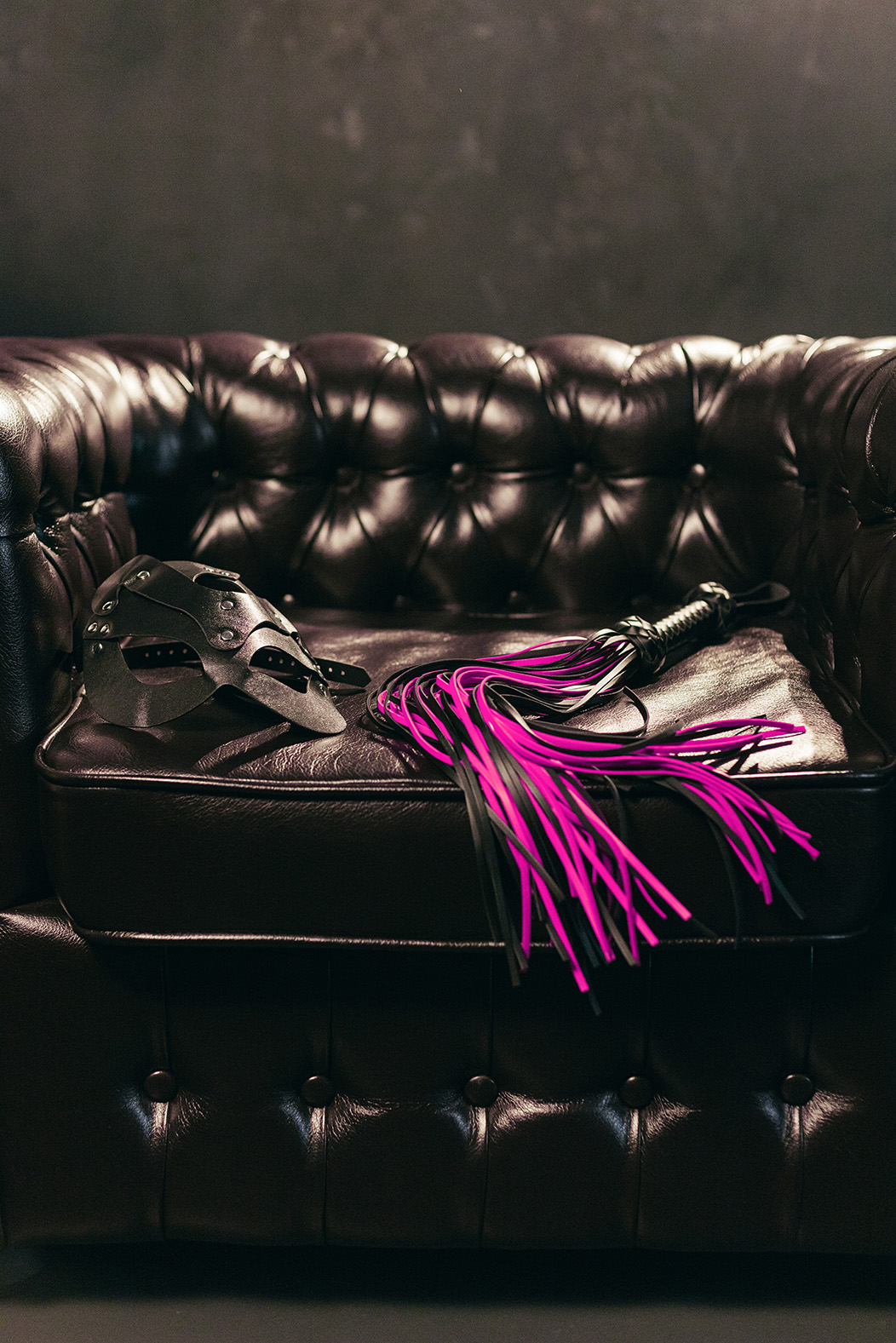 A leather chair with a mask and whip BDSM Duo Sessions